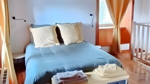 Une chambre à coucher avec un lit, un plancher en bois et une fenêtre avec des rideaux.