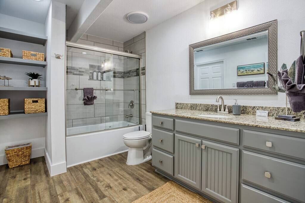 A bathroom with a shower, toilet, and vanity with drawers.