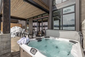 Ein Whirlpool mit Bedienfeld, Holzboden und Blick auf eine verschneite Landschaft.