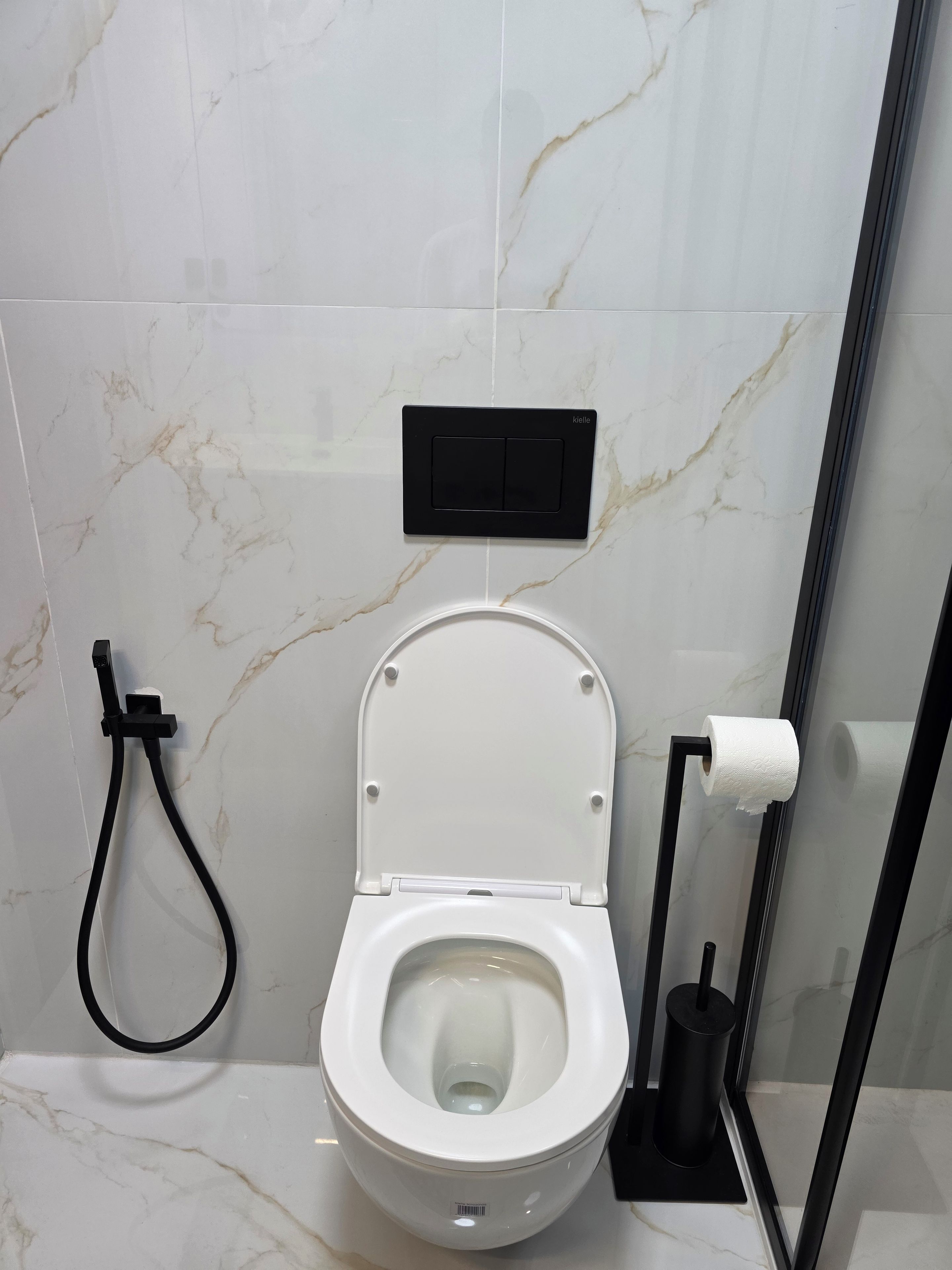 A modern bathroom with a toilet, a bidet, and a toilet paper holder.