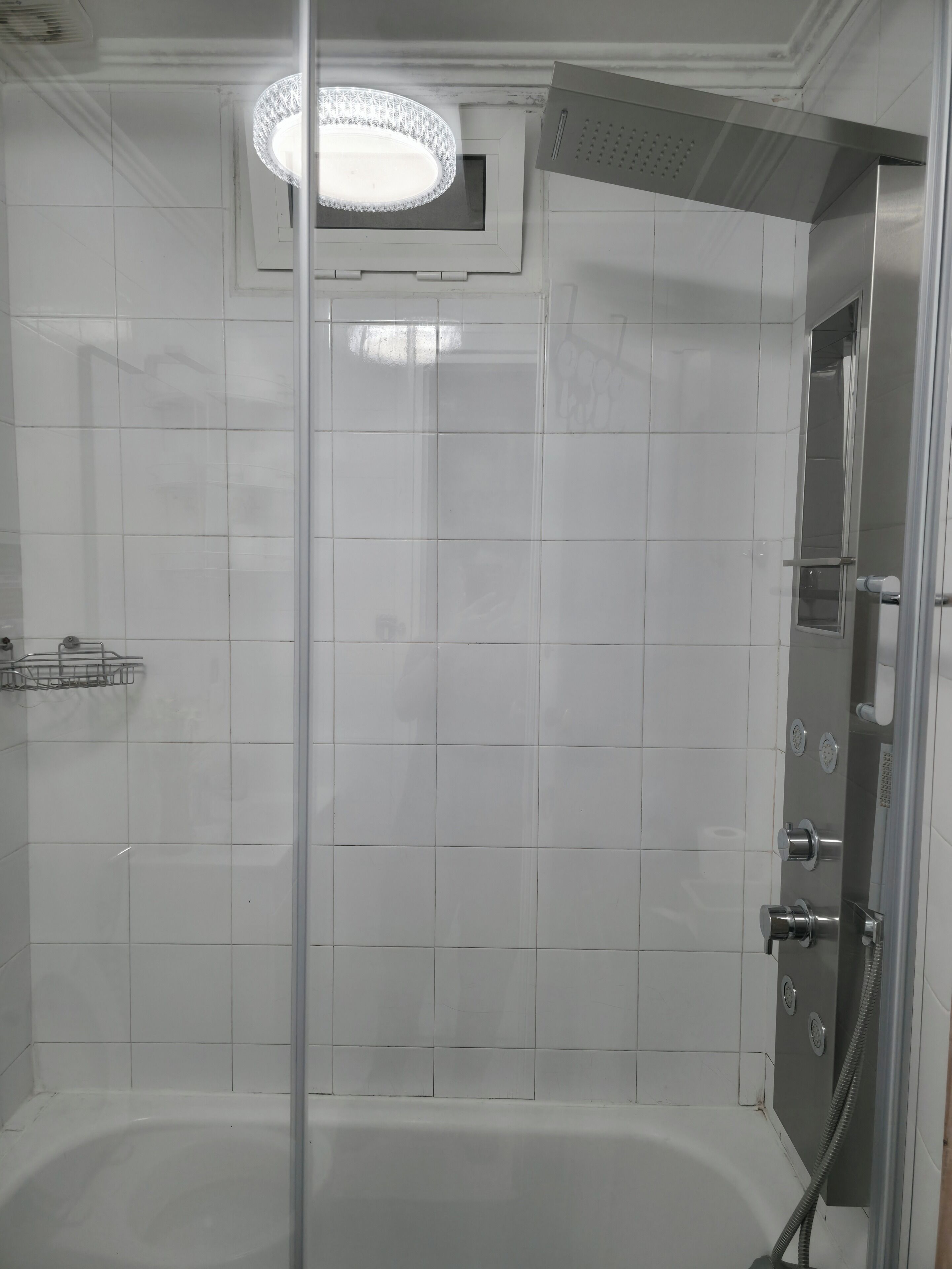 Eine moderne Duschkabine mit Glastür, integriertem Licht und Handbrause.