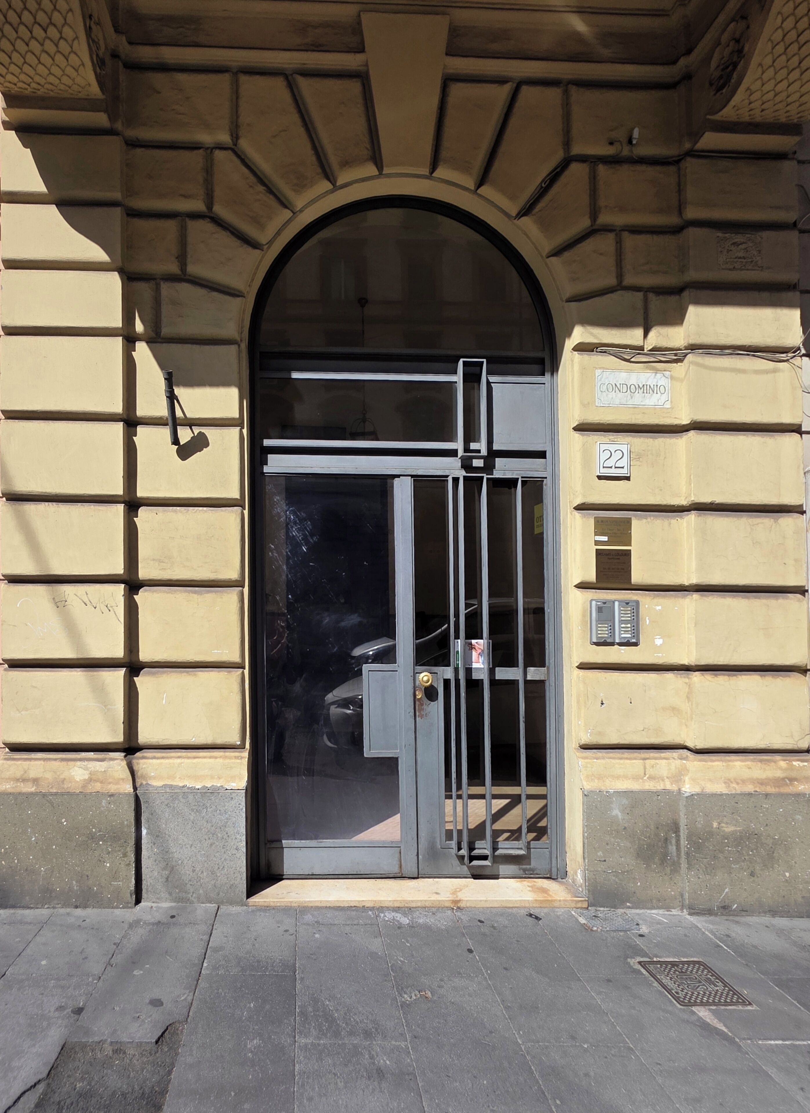 Ein Gebäudeeingang mit einem Metallgitter, einer Tür und einem Schild mit der Aufschrift 'CONDOMINIO 22'.