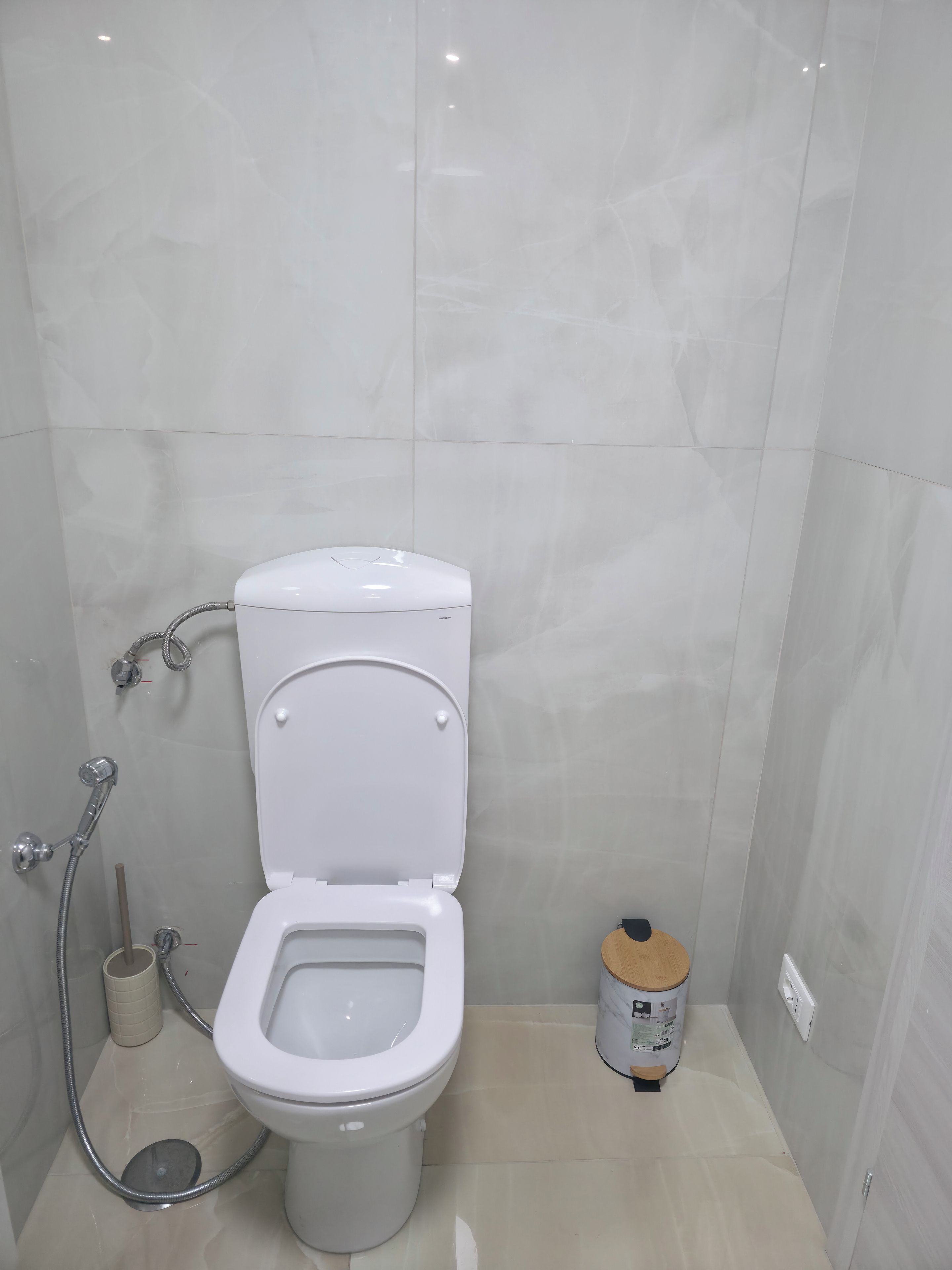 A bathroom with a toilet, a shower, and a toilet paper holder.