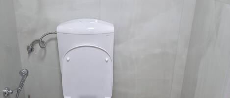A bathroom with a toilet, a shower, and a toilet paper holder.