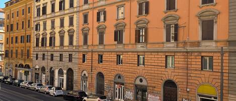 A multi-story building with a row of parked cars and a tram line in front.