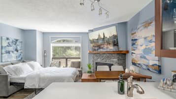 Une chambre moderne avec un lit, un bureau et une vue sur le paysage urbain, visible par la fenêtre.