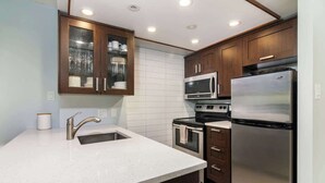 Eine moderne Küche mit einem Edelstahl-Kühlschrank, einer Mikrowelle, einem Backofen und einem Spülbecken mit Armatur.