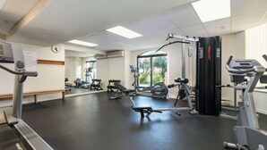 Ein Fitnessstudio mit Laufbändern, Kraftgeräten und einer Hantelbank.