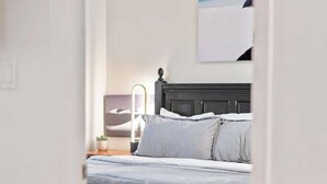 A bedroom with a bed, pillows, a nightstand, a lamp, and a wall-mounted artwork. - Luxe 2-Bed Ski-in Ski-out, On Hill (Whistler)