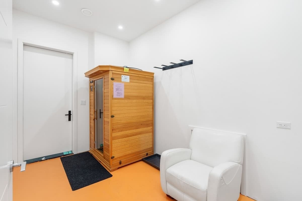 Habitació amb sauna, una cadira blanca i una porta blanca.