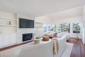 A modern living room with a fireplace, white sofas, and large windows. - Ocean View Luxury Retreat in West Vancouver (West Vancouver)