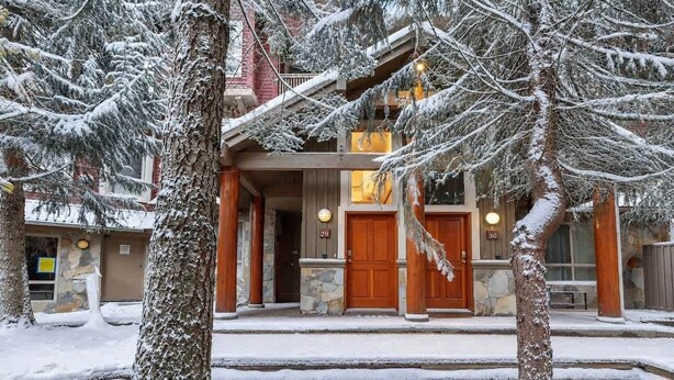 A two-story building with a stone facade, wooden doors, and a balcony. - Symphony - Walk to village & slopes - Luxury 4-bed (Whistler)