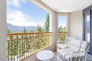 Ein Balkon mit Blick auf Berge, einem weißen Tisch und zwei weißen Stühlen.
