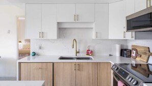 Una cocina moderna con gabinetes blancos, una estufa de acero inoxidable y un microondas integrado.