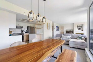 Eine moderne Küche mit weißen Schränken, einem Holztisch und Pendelleuchten.