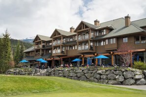 Ein mehrgeschossiges Lodgehaus mit Balkonen, Sitzgelegenheiten im Freien und einer Steinschrankmauer.