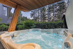 A hot tub with a wooden deck overhead, surrounded by lush greenery and tall trees. - Timber Haven - Luxury Ski in Ski out - Kadenwood (Whistler)