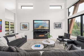 Ein modernes Wohnzimmer mit Kamin, großen Fenstern und Kunstwerken an den Wänden.