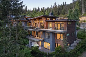 A multi-story modern house with a balcony, large windows, and a hot tub in the backyard. - Timber Haven - Luxury Ski in Ski out - Kadenwood (Whistler)