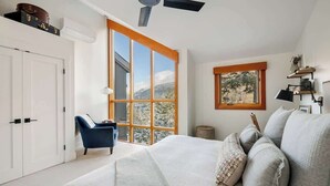 A bedroom with a large window, a bed, a chair, and a wardrobe. - Luxe 5-BED Scandinave Retreat - Walk to Slopes (Whistler)