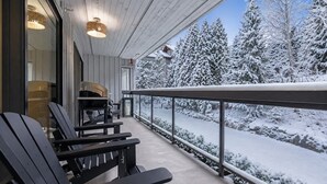 Un espacio exterior techado con sillas Adirondack, una mesa y vistas a un paisaje cubierto de nieve.