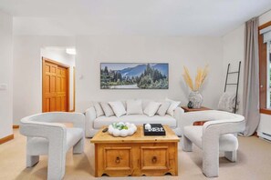 A living room with a sofa, two armchairs, a coffee table, a painting, and a vase with dried plants. - 3-BDRM | Whistler Village | Walk to Hill | Hot Tub (Whistler)