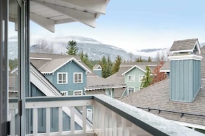 Ein Wohngebiet mit Häusern, einem Balkon und einer Bergkulisse im Hintergrund.