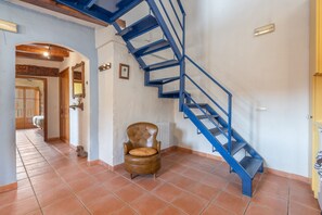 A staircase with blue railings, a brown leather chair, and a tiled floor. - Apartment 'Cal Capdevila Blau' with Mountain View, Wi-Fi and Air Conditioning (Pira)