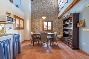 A kitchen with a stone ceiling, a dining table with chairs, a microwave, and a cabinet with glassware. - Apartment 'Cal Capdevila Blau' with Mountain View, Wi-Fi and Air Conditioning (Pira)