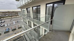 A modern building with a glass balcony overlooking a parking area and distant buildings. - Coastal Couple Hideaway in Oostduinkerke (Koksijde)