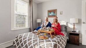 Ein Schlafzimmer mit Bett, Nachttischen, einem Fenster mit Jalousien und einem Bild an der Wand.