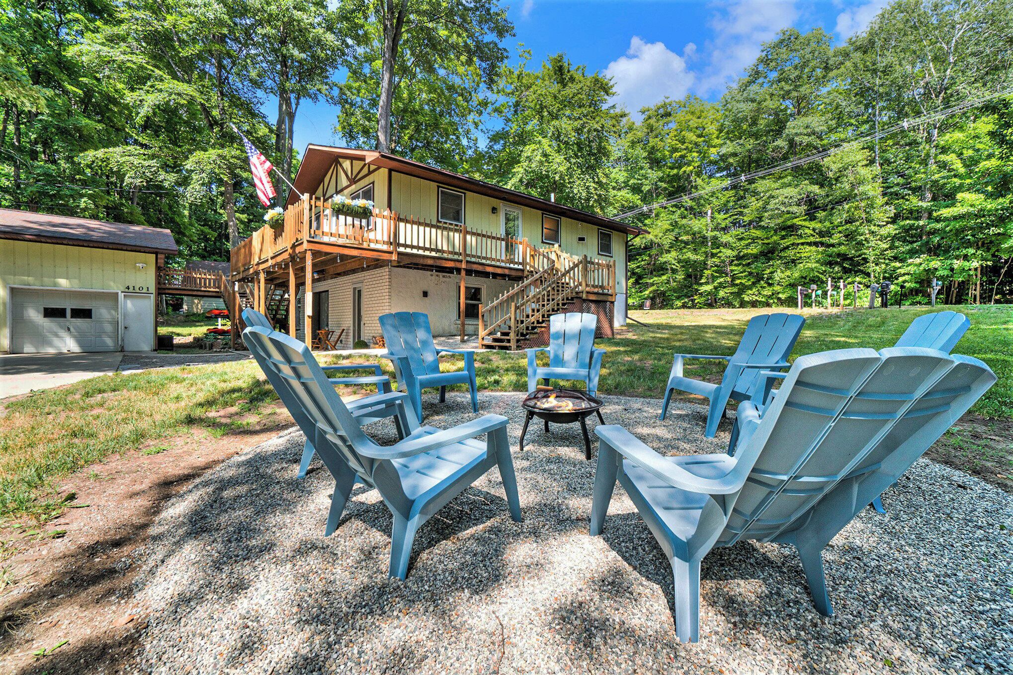 A cabin with a deck, outdoor seating, and a gravel area.