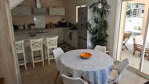 Una cocina moderna con armarios blancos y una zona de comedor con una mesa redonda y sillas blancas.