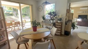 Un comedor con una mesa redonda, sillas, una estantería y vistas al exterior.
