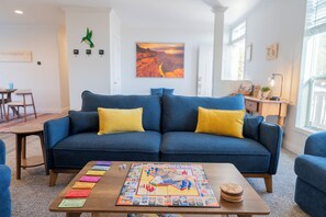 A living room with a blue sofa, a coffee table with a board game, and a painting on the wall. - Grand Canyon Escape in Williams sleeps 6 (Williams)