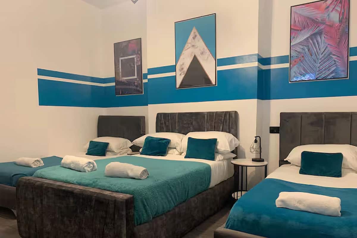 A hotel room with two beds, teal bedding, and a wooden headboard.