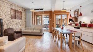 Un interior moderno con una pared de piedra, un sofá, una mesa de comedor con sillas y una zona de cocina.
