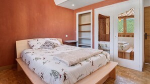 Un dormitorio con cama, mesita de noche, armario y puerta que da a un espacio exterior.