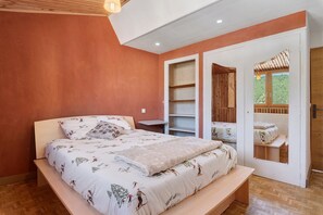 A bedroom with a bed, a bedside table, a wardrobe, and a door leading to an outdoor area. - L’Authentique du Vercors, Wood Charm & Modern Comfort (Villard-de-Lans)