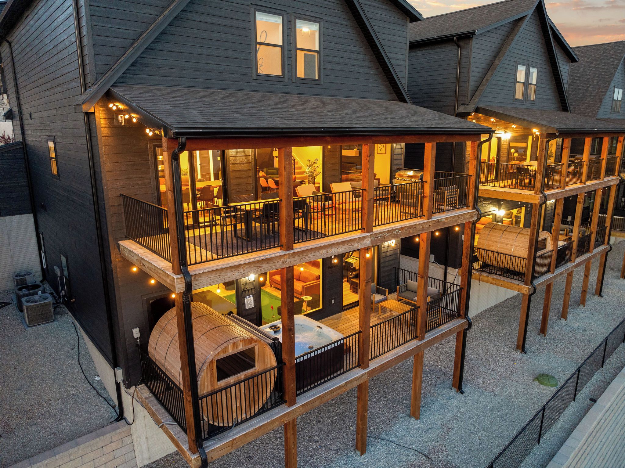Een meerlaags houten gebouw met balkons, terras en een hottub.