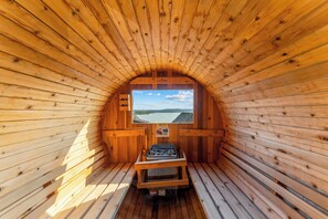 A sauna with wooden walls and a bench, a window with a view of a lake, and a caution sign. - 2 Homes 2 Golf Simulators Sleeps 51 HotTubs Saunas (Branson)