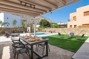 A covered outdoor area with a pool, dining table, and chairs. - Villa Avia Pefkos by Villa Plus (Pefki)