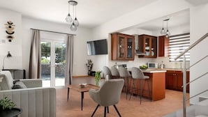 Una cocina moderna con armarios de madera, un comedor con mesa y sillas, y una escalera que sube a un nivel superior.