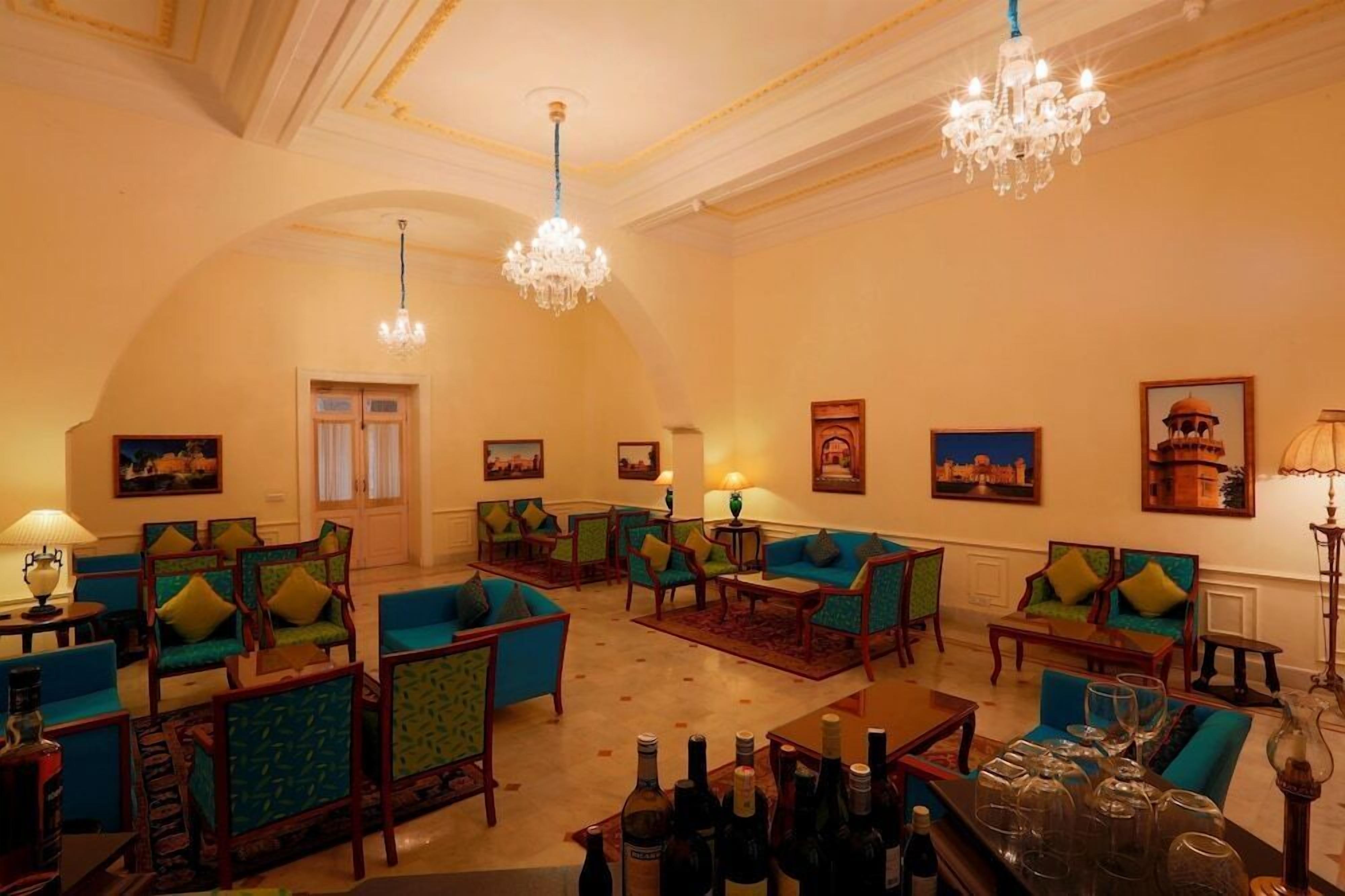 A hotel lobby with a high ceiling, chandeliers, and a seating area with sofas and armchairs.