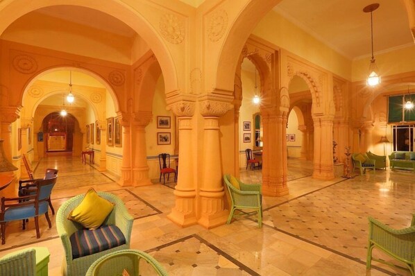 A spacious lobby with high ceilings, arches, and a central seating area with chairs and sofas.