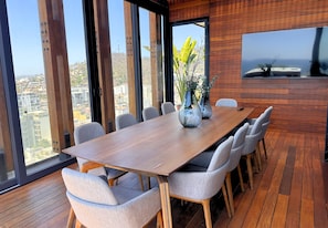 Ein moderner Essbereich mit Holztisch und -stühlen, großen Fenstern und Blick auf die Stadt.
