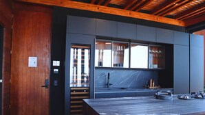 A modern kitchen with a marble countertop, wooden ceiling beams, and built-in cabinets. - Departamento con chalet (Puerto Vallarta)