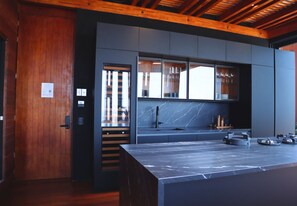 Eine moderne Küche mit Marmorarbeitsplatte, Holzbalkendecke und eingebauten Schränken.