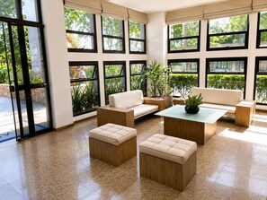 Ein geräumiger Raum mit großem Fenster, einem Sofa, einem Couchtisch und einem kleinen Tisch mit Pflanze.