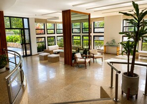 Eine großzügige Lobby mit Sitzgelegenheiten, großen Fenstern und einer Zimmerpflanze.
